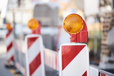 Drei Leitbarken stehen vor einer Absperrung