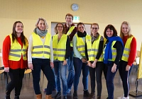 Gruppenbild mit acht Personen, die in die Kamera lächen und gelbe Warnwesten tragen.